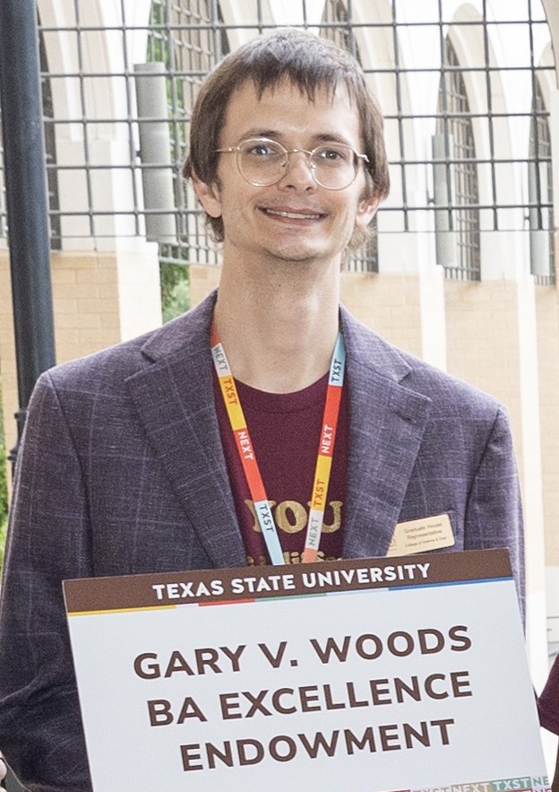 Photograph of Samuel Kimmel holding a thank you sign for the Gary V. Woods BA Excellence Endowment