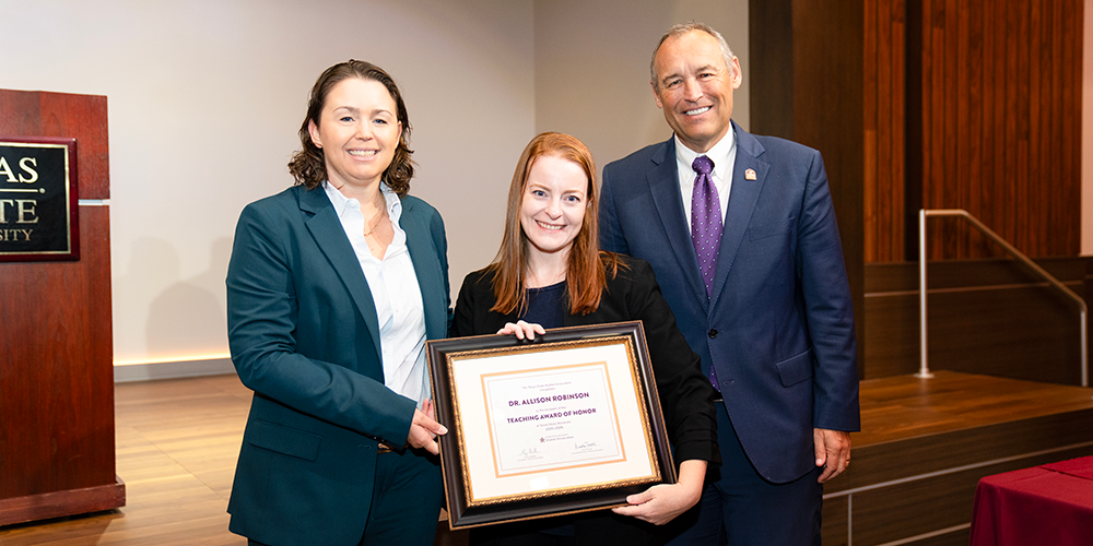 Dr. Allison Robinson with her Teaching Award of Honor certificate on Faculty Awards Night standing with Texas State President Kelly Damphousse and Assistant Vice President of Alumni Engagement Kristi Troxel