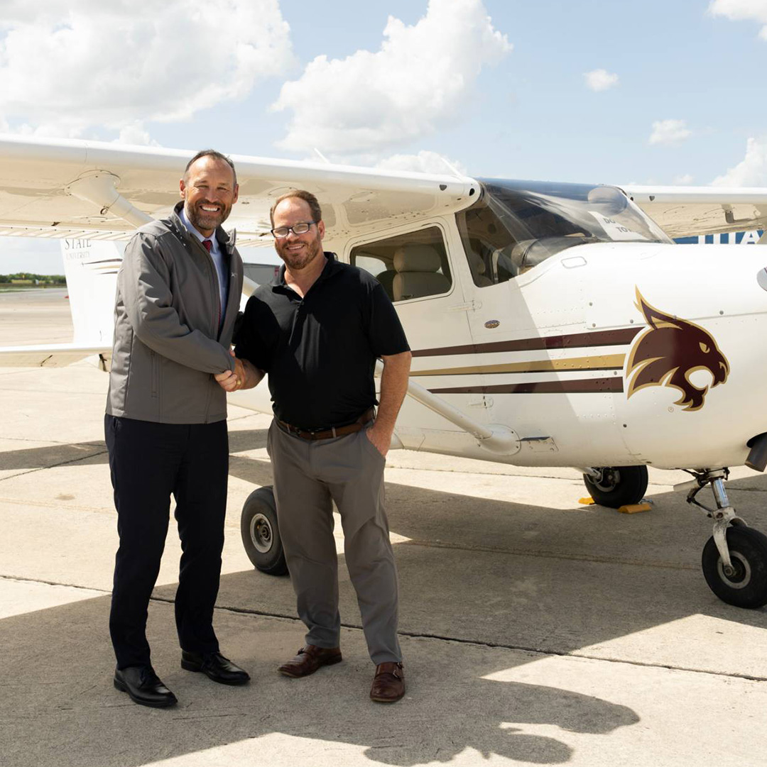 Kelly Damphousse shaking hands with Coast Flight President Heath Jameson in front of a Bobcat airplane