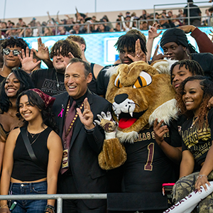 Students in the stands at a football game with President Damphousse and Boko the Bobcat