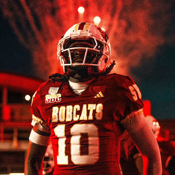 Bobcat football player on field with fireworks in the background