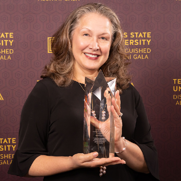 Woman holding an award at the Distinguished Alumni Gala