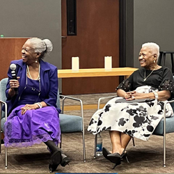 Two Black women sitting in chairs and laughing