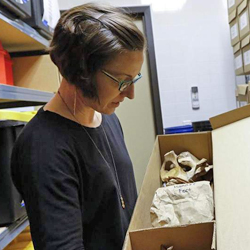 woman looking into cardboard box that contains skeletal remains