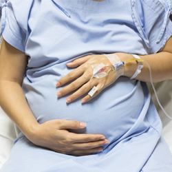 woman in hospital gown holding pregnant stomach