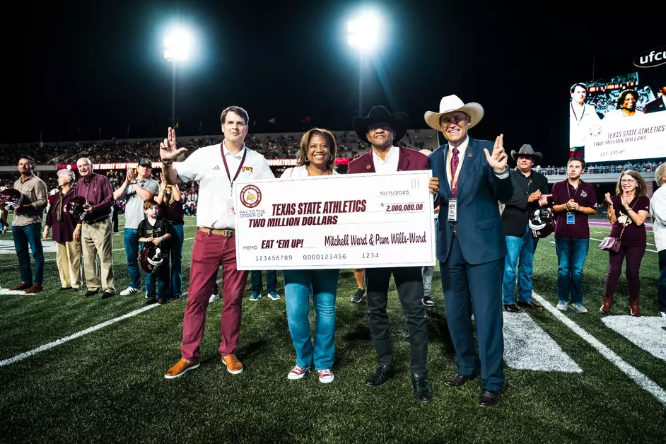 Mitchell Ward and Pam Wills-Ward presenting a check on the Texas State football field