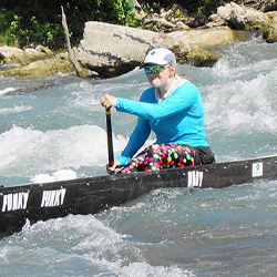 woman steering canoe down rapids on river
