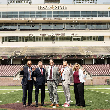 TXST President Kelly Damphousse and Athletic Director Don Coryell with representatives from UFCU on the Texas State Football Field 50 yard line in UFCU Stadium